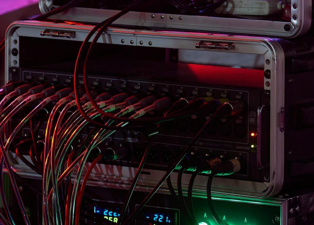 Close-up of audio equipment with colorful stage lights at a live event, showcasing professional sound gear.